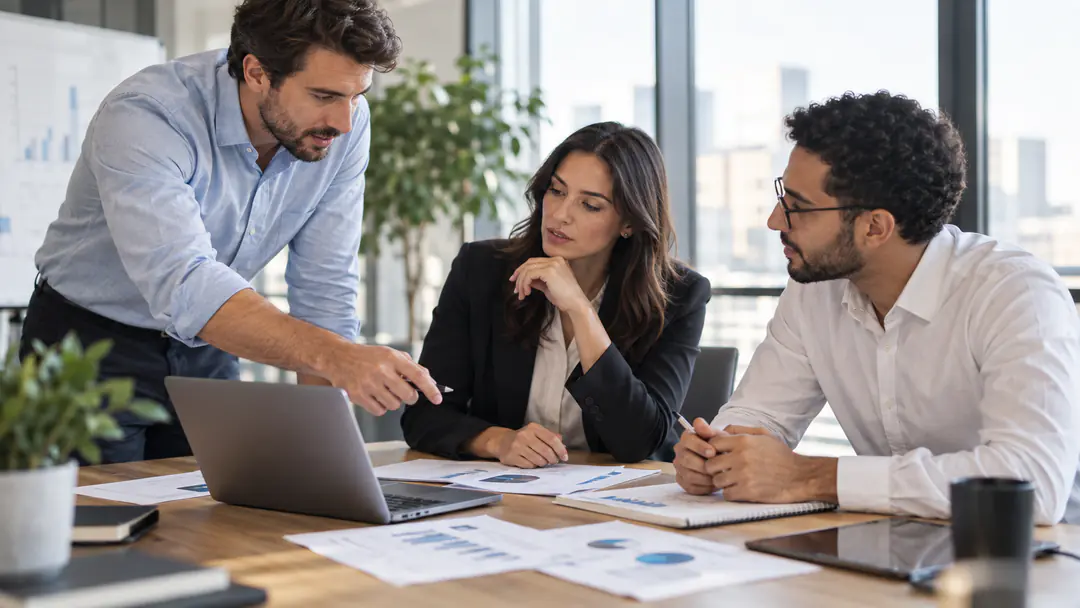 Business team collaborating around a laptop and printed charts